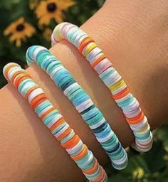 three bracelets with different colors and designs on the wrist, one is multicolored