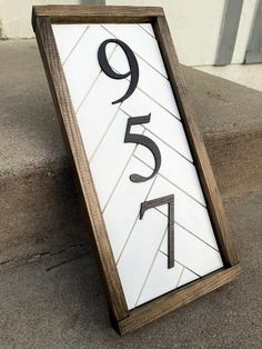 a house number sign sitting on the sidewalk