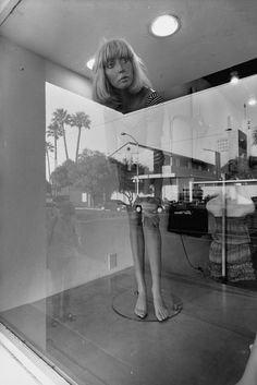 a woman's reflection in the window of a clothing store