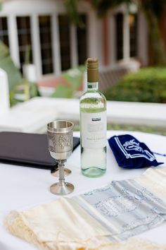 a bottle of wine sitting on top of a table next to a silver goblet