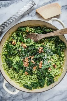 a pan filled with spinach and other food on top of a marble countertop