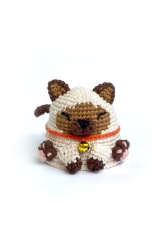 a small crocheted stuffed animal wearing a white and brown outfit