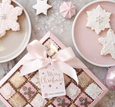 pink and white christmas cookies in a gift box on a marble table with other decorations