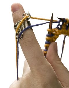 a hand holding a yellow string with two rings on it and an arrow in the middle