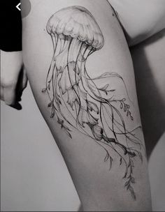 a black and white photo of a woman's thigh with a jellyfish tattoo on it