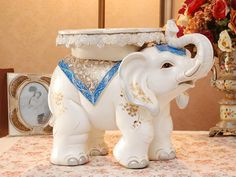 an elephant figurine sitting on top of a table next to a vase with flowers