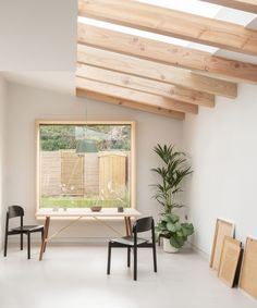 an empty room with two chairs, a table and a window in the center that has wooden slats on it