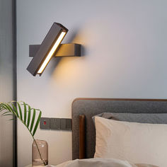 a lamp that is on the side of a wall next to a bed with pillows