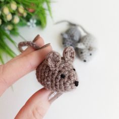 two tiny crocheted mice sitting on top of each other in front of flowers