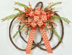 an orange and white bow is hanging on a wreath