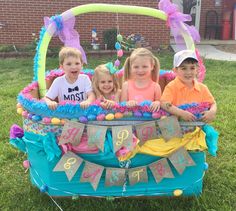 three children are sitting in a wagon decorated with decorations