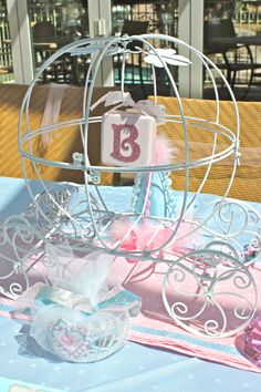 a table topped with a cake covered in pink and blue frosted icing next to a metal cage