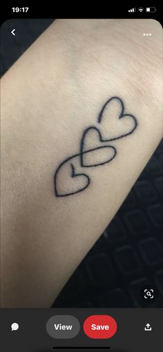 a small tattoo on the wrist with two hearts and an arrow that is in the shape of a heart