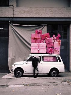 a man standing next to a white car with lots of presents on top