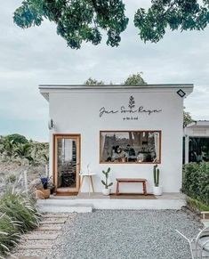 a small white building with plants in front of it