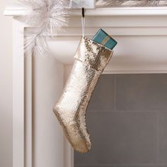 a gold christmas stocking hanging from a mantel above a fire place mantle with silver feathers