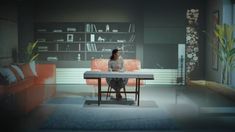 a woman sitting at a table in the middle of a room with couches and bookshelves