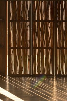 the sun is shining through bamboo screens in an empty room with wood flooring and wooden walls