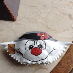 a paper mache with a clown face painted on it's side and a flower in its mouth