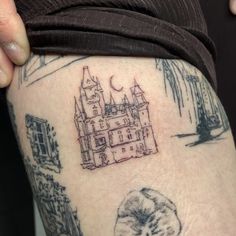 a woman with a tattoo on her thigh shows off the back of her leg, which has an image of a castle in it