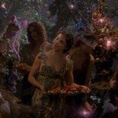 a group of people standing around each other in the woods with fairy costumes on them