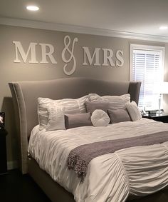 a large bed sitting in a bedroom under a mr and mrs decal on the wall