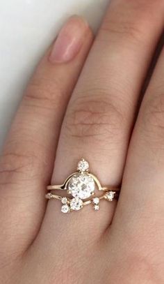 a woman's hand wearing a gold ring with an oval shaped diamond on it