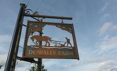 a rusty sign that says downhill farm on the side of a pole with trees in the background