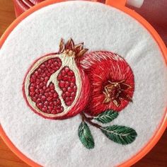 an embroidered pomegranate on a white and orange hoop