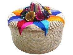 a round basket with multi colored ribbons and decorations on the top, sitting in front of a white background