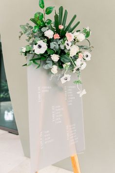 a vase filled with flowers sitting on top of a wooden easel next to a wall