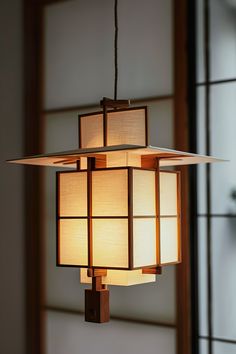 a light fixture hanging from the ceiling in a room with large windows and wood trimmings