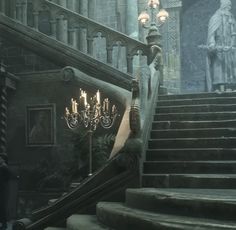 an old staircase with chandeliers and statues in the background