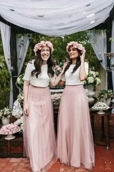 two women standing next to each other wearing long skirts