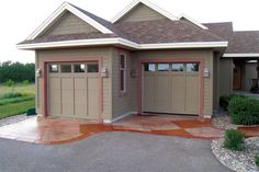 two garages in front of a house with landscaping around them