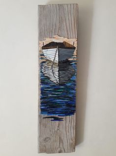 a wooden wall hanging with a painting of a sailboat on it's side