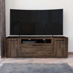 a flat screen tv sitting on top of a wooden entertainment center in a living room