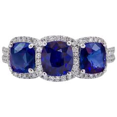 three stone ring with blue sapphires and diamonds on the sides, set in 18k white gold