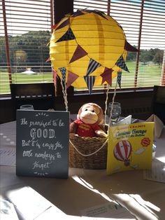 a teddy bear sitting in a basket on top of a table next to a sign