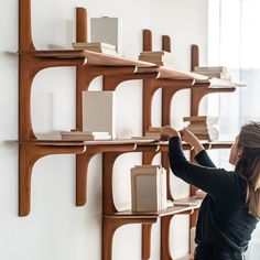 a woman is placing books on the wall in front of shelving units that are lined with books