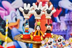 mickey mouse cake pops are sitting on a table with other disney characters in the background