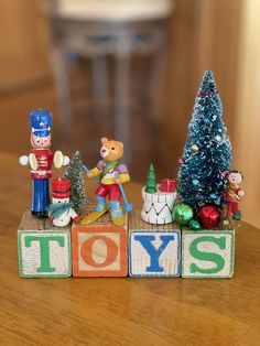 small toy figurines are sitting on blocks that spell out toys