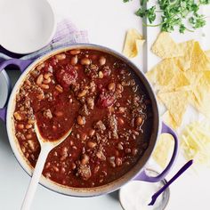 a pot filled with chili and beans next to tortilla chips