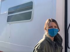 a woman wearing a face mask standing in front of a trailer