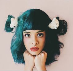 a woman with green hair and two white teddy bears on her head is posing for the camera