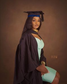 a woman wearing a graduation cap and gown poses for a photo in front of a brown background