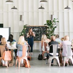 a group of people sitting at tables in front of a blackboard