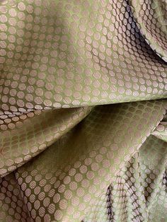 a close up view of a green and brown fabric with small circles on the side