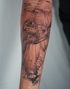 a man's arm with a turtle and coral tattoo on it