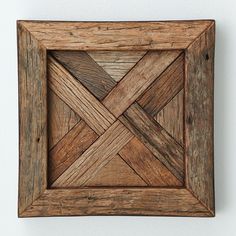 a wooden frame with an intricate design in the center on a white wall, made out of wood planks